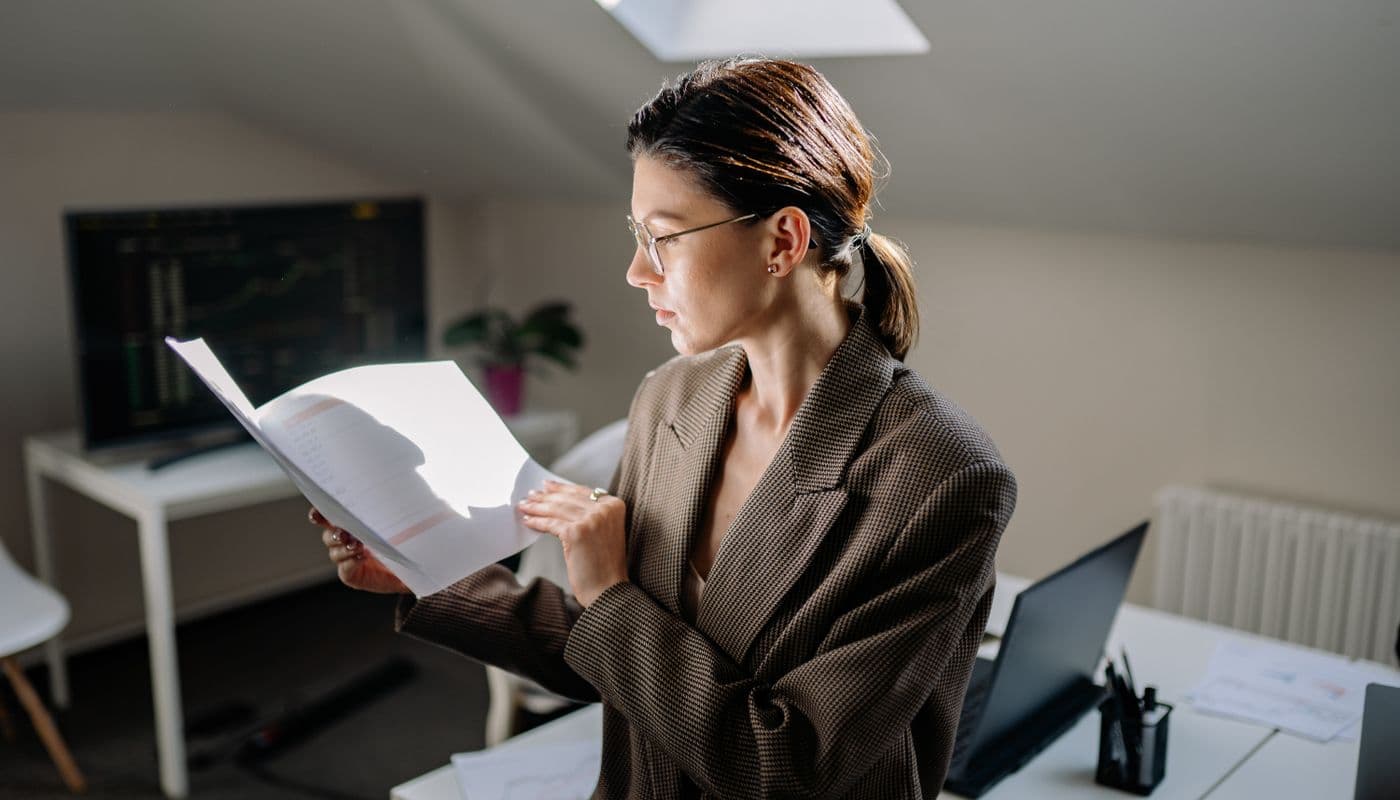 Une personne relisant des documents imprimés posés sur un bureau