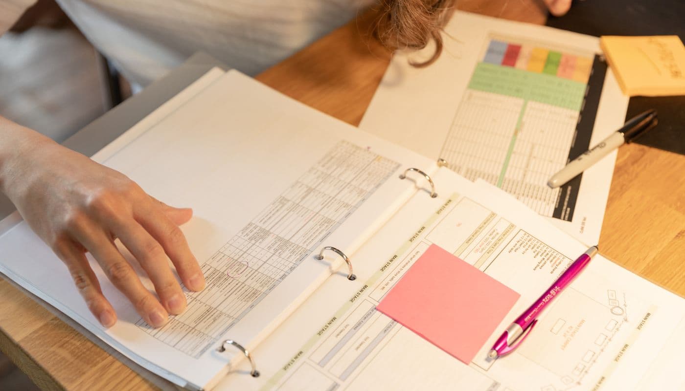 Une personne lisant une pile de documents papier à son bureau